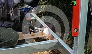 Worker in safety uniform welding steel structure in construction site