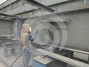 Worker is sandblasting a welding surface and steel structure with pressure blasting pot for create surface profile of steel before