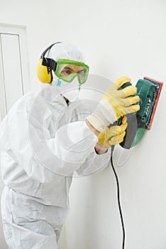 Worker with sander at wall filling