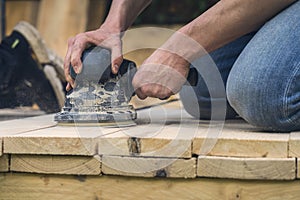 Worker sanding wood planks with a grinder
