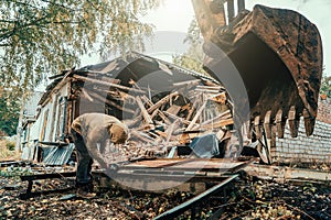 Worker sawing iron at construction site when demolishing house with excavator. Construction destroying