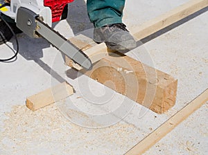 Worker sawing a wooden plank with a chainsaw