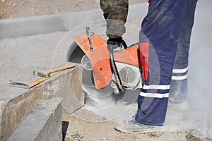 A worker saws a concrete block with a circular saw.