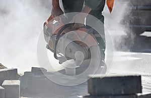 A worker saws concrete with a hand saw and builds a road.