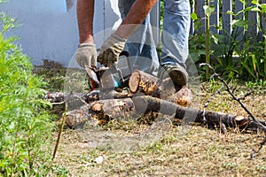 The worker saws the log with an electric saw.