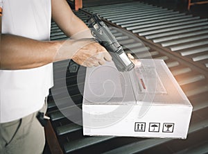 Worker scanning barcode scanner with red laser on parcel box. Shipment, Computer equipment for warehouse inventory management