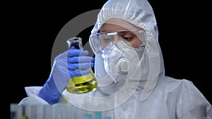 Worker of scientific lab analyzing flammable liquid in flask, toxic igniter