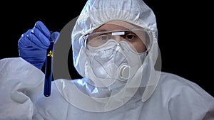 Worker of scientific lab holding test tube with biological hazard sign, harm