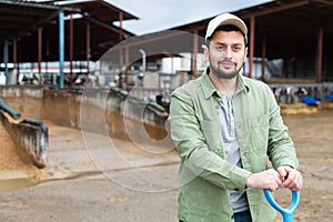 Worker scrapes soy husks with a shovel of mixed feed on farm