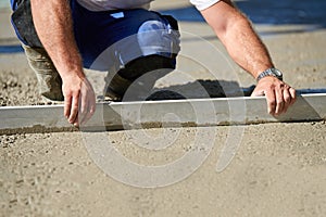 Worker screeding cement floor with screed