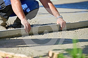 Worker screeding cement floor with screed