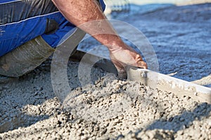 Worker screeding cement floor with screed photo