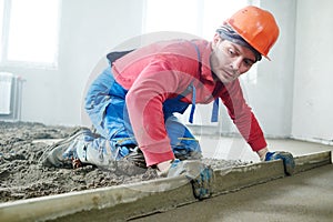 Worker screeding indoor cement floor with screed