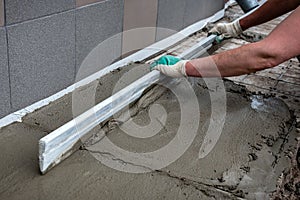 Worker screeding outdoor cement floor with screed photo