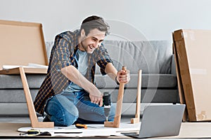 Worker with screwdriver assembles and installs furniture in living room