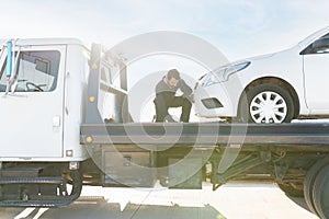 Worker securing that the car is safe on the tow truck platform