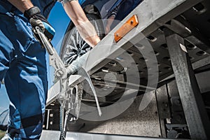 Worker Securing Car on Towing Truck with Tie Down Belts