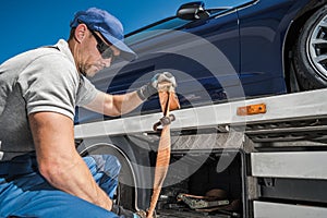 Worker Securing Repossessed Vehicle on His Towing Truck