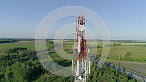 Worker servicing cellular antenna in front of telecommunication tower