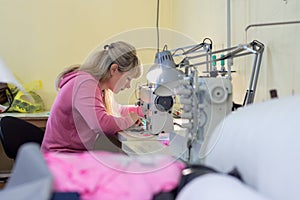 Worker in sewing workshop sews on a professional sewing machine