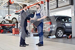 Worker Shaking Hands with Client in Car Service Shop