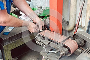 Worker sharpening tools in workshop using grinding paper