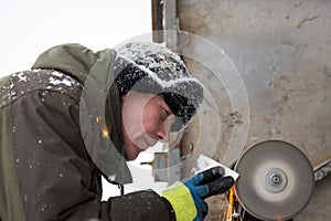 Worker sharpens a chisel on the emery wheel