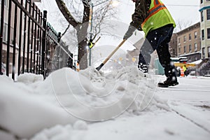 worker shoveling snow off a public sidewalk