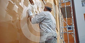 A Worker Skillfully Paints the Wall in Rich Brown with a Steady Hand and Roller