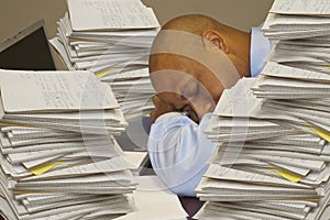 Worker Sleeping While Surrounded With Stacks of Paper Work