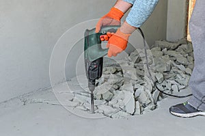 Worker smashes concrete floor with electric hammer drill