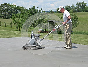 Worker smoothing concrete with a power trowel