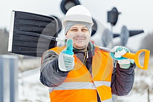 Worker with snow shovel near signal beacons in snowy day