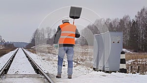 Worker with snow shovel on a railway crossing