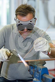Worker soldering copper pipe with blowtorch