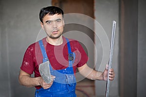 A worker with spatula and level in workwear makes