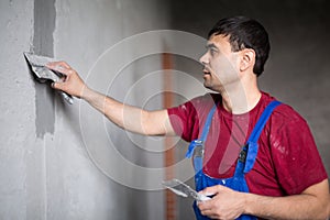 A worker with spatula in workwear makes repairs