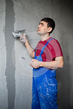 A worker with spatula in workwear makes repairs