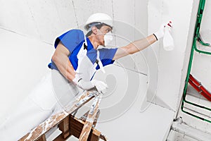 Worker spraying ceiling with spray bottle