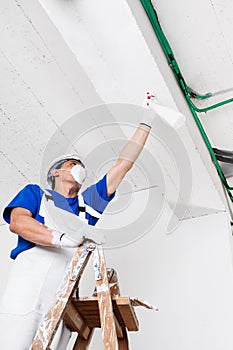 Worker spraying ceiling with spray bottle