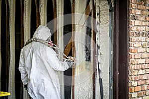 Worker spraying closed cell spray foam insulation on a home wall