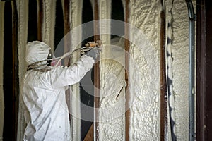 Worker spraying closed cell spray foam insulation on a home wall