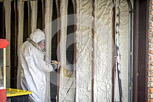 Worker spraying closed cell spray foam insulation on a home wall