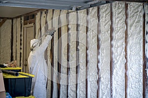 Worker spraying closed cell spray foam insulation on a home wall