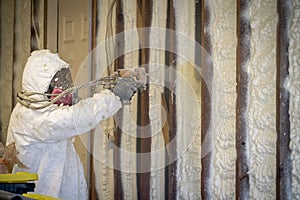 Worker spraying closed cell spray foam insulation on a home wall