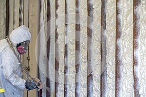 Worker spraying closed cell spray foam insulation on a home wall photo