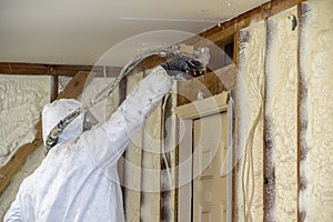 Worker spraying closed cell spray foam insulation on a home wall photo