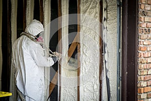 Worker spraying closed cell spray foam insulation on a home wall photo