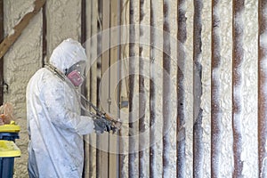 Worker spraying closed cell spray foam insulation on a home wall