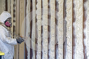 Worker spraying closed cell spray foam insulation on a home photo
